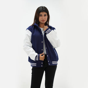 Detail shot of white leather sleeve and ribbed waistband with navy and white striped trim on women's hooded varsity jacket