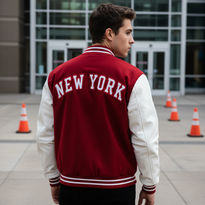 Person wearing a red and white 'New York' letterman jacket standing in front of a building with traffic cones.