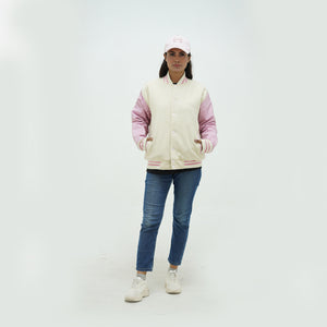 Full view of women's off white and pink varsity jacket showcasing complete fit, ribbed hem, and elegant cream-pink color combination