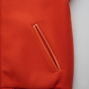 Close-up of an orange jacket with a  pocket on a white background