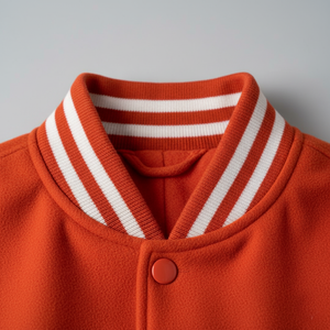 Close-up of an orange sweater with a white striped collar on a gray background 