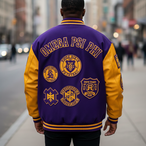 Person wearing a purple and yellow Omega Psi Phi letterman jacket on a city street.