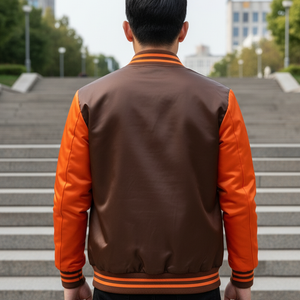 Person wearing a brown and orange varsity jacket standing on steps outdoors. 