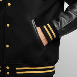 Black varsity jacket with gold buttons and trim on a gray background