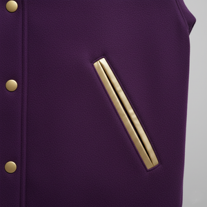Close-up of a purple garment with gold buttons and pocket a gold stripe on a gray background