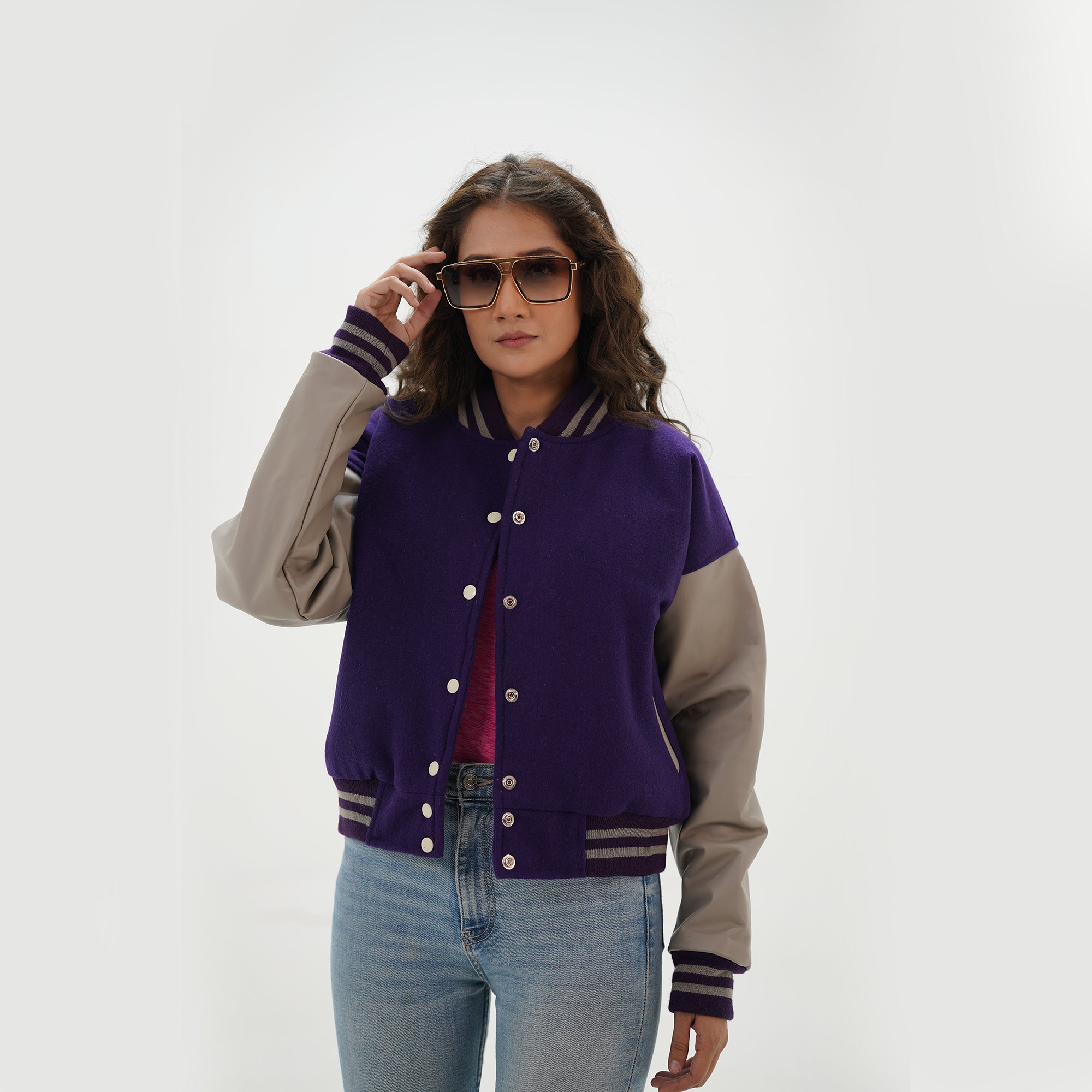 Close-up detail of purple and gray crop varsity jacket featuring wool and leather sleeve junction with ribbed collar on cropped style