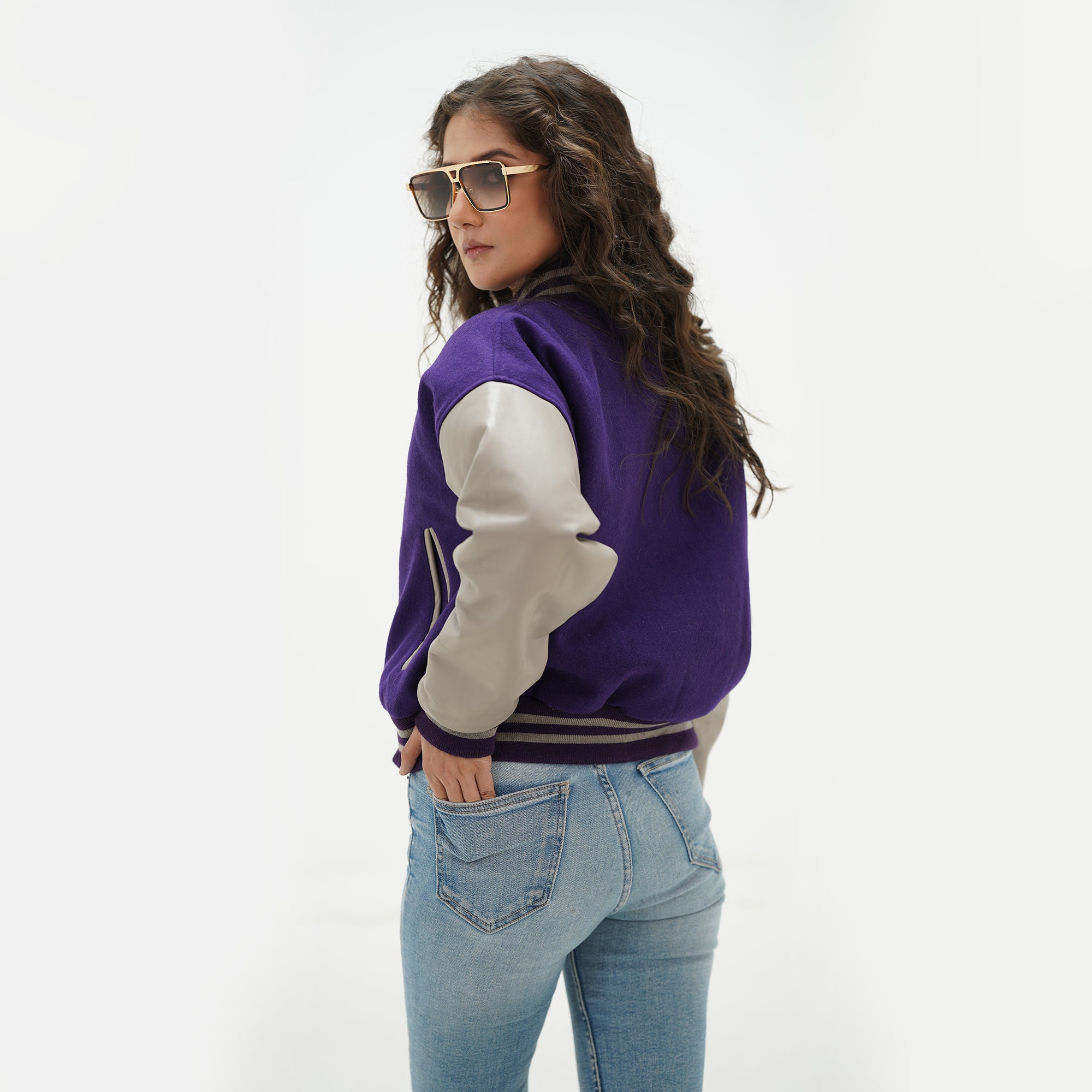 Back view of girls purple and gray crop varsity jacket displaying purple Melton wool body, gray genuine leather sleeves, and ribbed cropped waistband