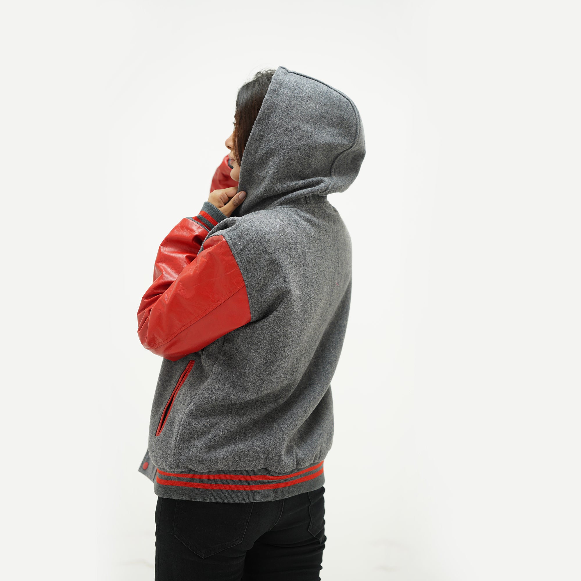 Back view of red and gray wool varsity jacket displaying red leather sleeves and ribbed waistband detail