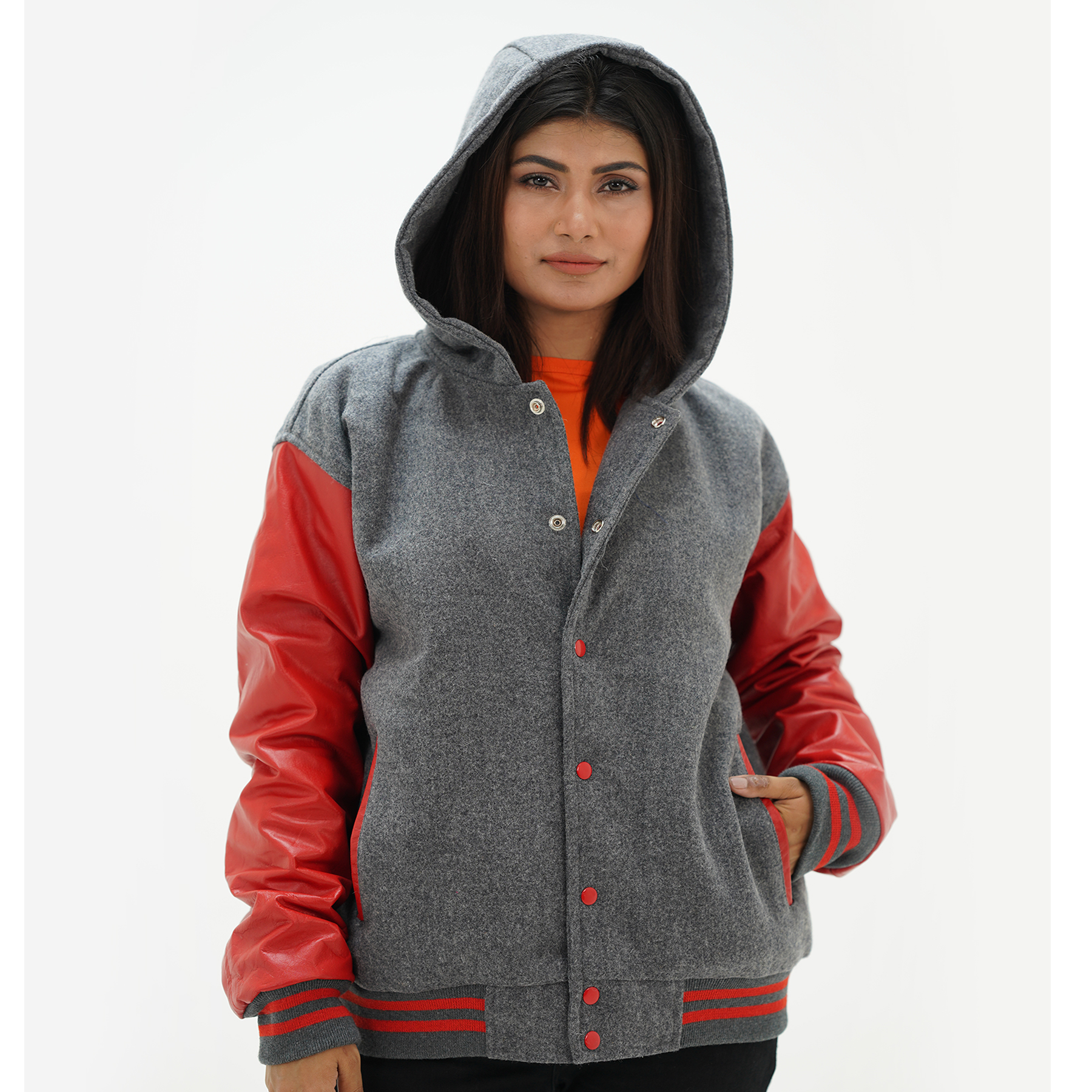 A woman wearing a red and gray varsity jacket with leather sleeves and a hood, featuring a standing collar and ribbed cuffs.
