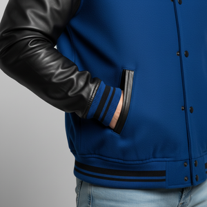 Blue varsity jacket with black leather sleeves on a gray background