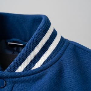 Close-up of a blue sweater with white stripes on the collar against a gray background