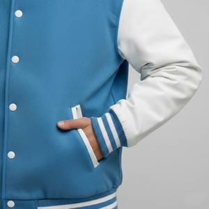 Blue and white varsity jacket with a hand in the pocket on a gray background