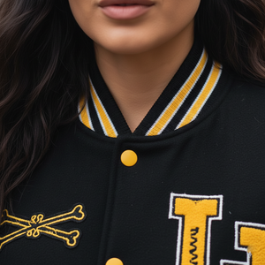 Close-up of a black letterman jacket with yellow accents and lettering.