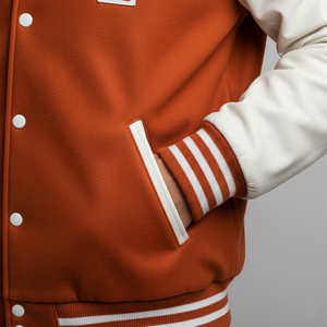 Close-up of a person wearing a brown varsity jacket with white accents on a gray background