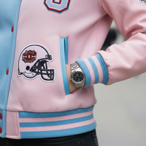 Pink and blue varsity jacket with a helmet patch and a watch on a blurred background