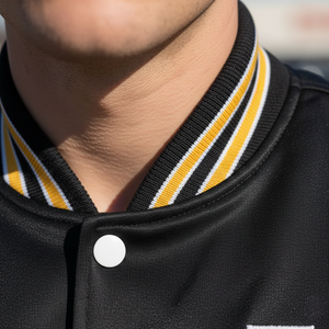Close-up of a person wearing a black varsity jacket with yellow and white striped collar.