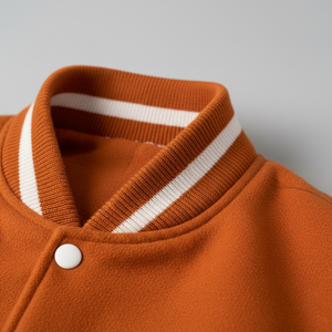 Close-up of an orange jacket with a white stripe on the collar against a gray background