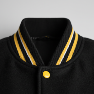 Black letterman jacket with yellow and white striped collar on a gray background