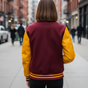 Person wearing a maroon and yellow varsity jacket on a city street.