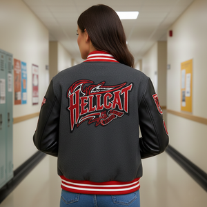 Person wearing a letterman jacket with 'HELLCAT' design in a school hallway