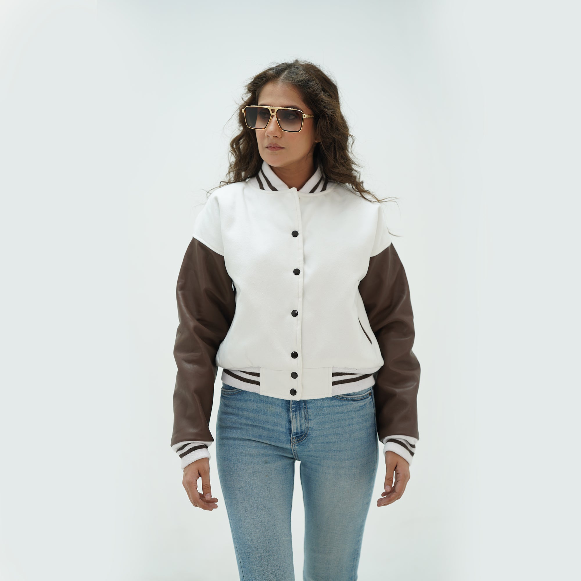 Three-quarter angle of women's white and chocolate brown varsity jacket highlighting snap buttons, side pockets, and elegant white-chocolate brown color pairing