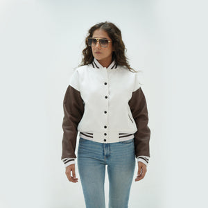 Three-quarter angle of women's white and chocolate brown varsity jacket highlighting snap buttons, side pockets, and elegant white-chocolate brown color pairing