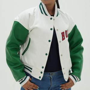 A woman wearing a white and green Chicago Bulls letterman jacket with ribbed cuffs and hem, featuring two side pockets and a quilted diamond lining. 