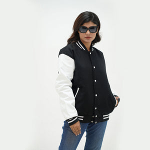 Women's black and white varsity jacket side angle - displaying monochrome design with white leather sleeves and ribbed cuffs detail