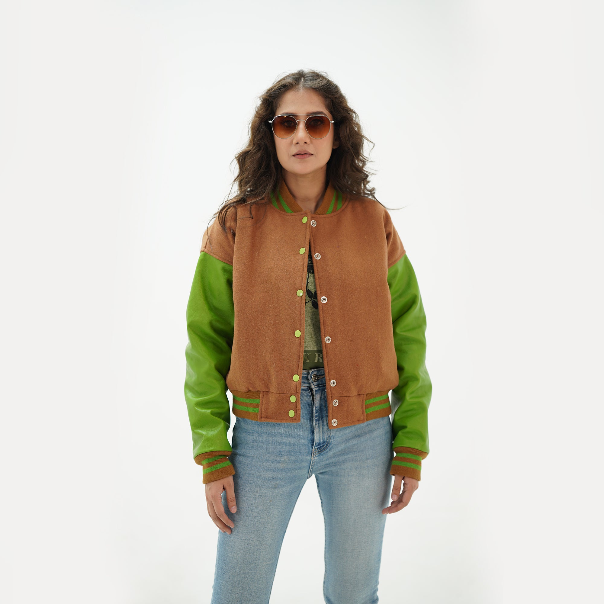 Three-quarter view of women's brown and parrot green varsity jacket highlighting snap buttons, side pockets, and unique brown-parrot green color pairing