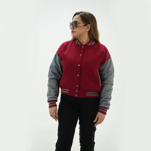 Side profile of women's magenta and gray letterman jacket showing gray leather sleeve construction, ribbed cuffs, and tailored feminine fit