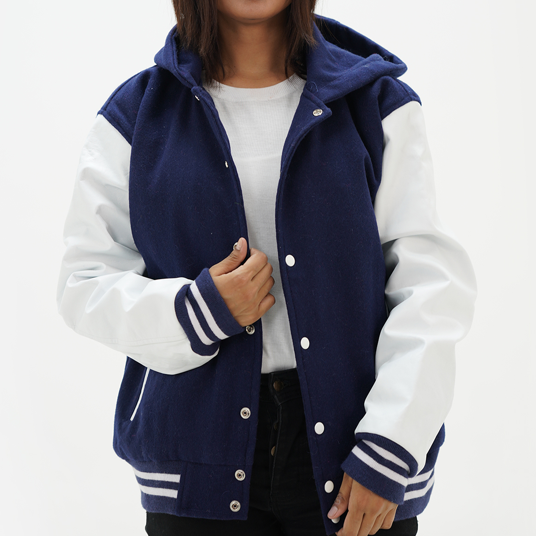 A woman wearing a navy blue and white Letterman hooded jacket with leather arms and a wool body, featuring a classic ribbed collar, cuffs, and hem.