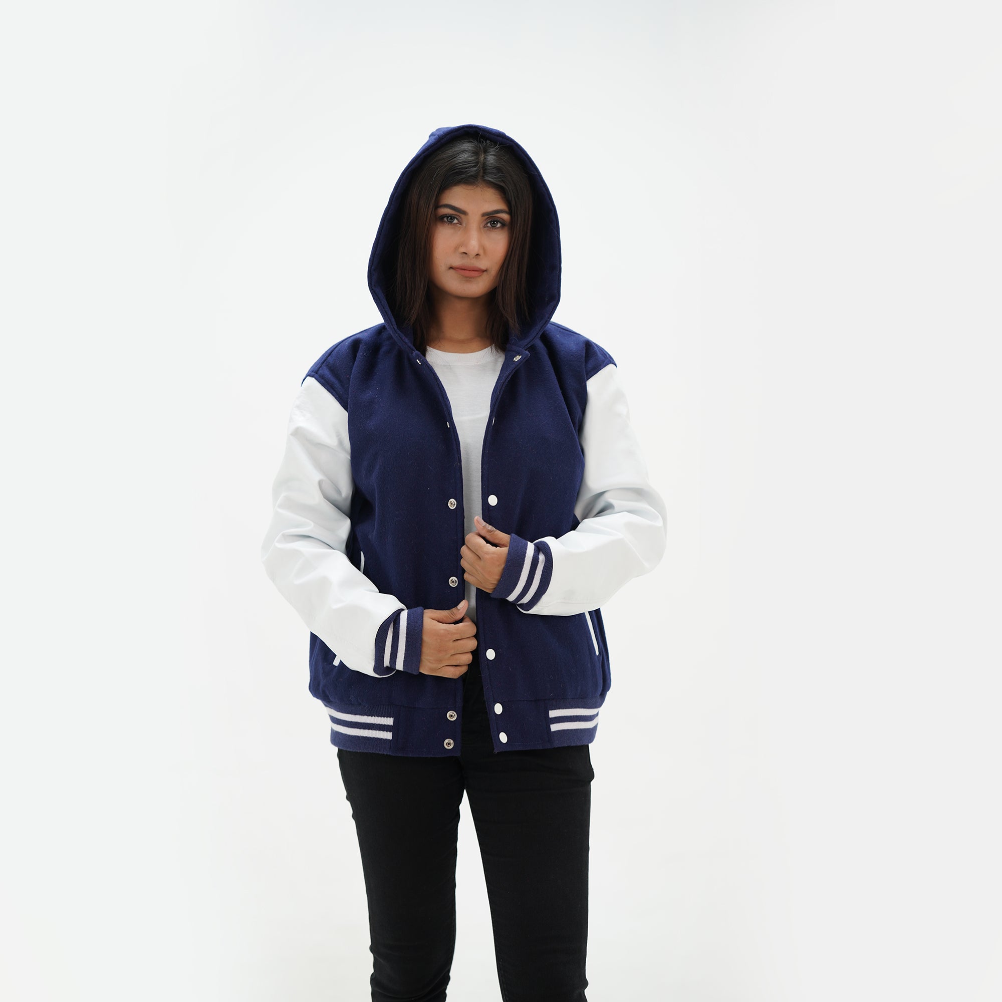 Three-quarter view of women's navy hooded letterman jacket with white leather sleeves showing premium wool body construction