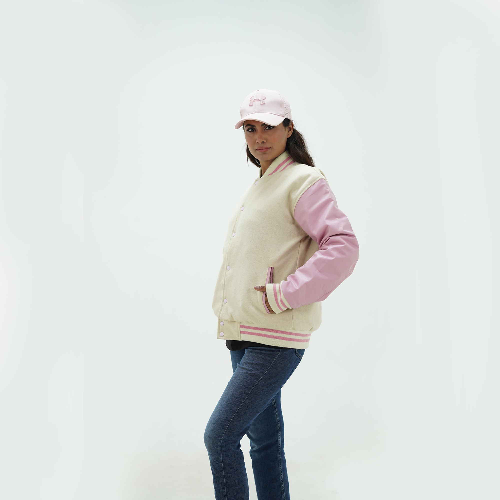 Side profile of women's off white varsity jacket with pink leather sleeves showing ribbed cuffs and feminine tailored silhouette