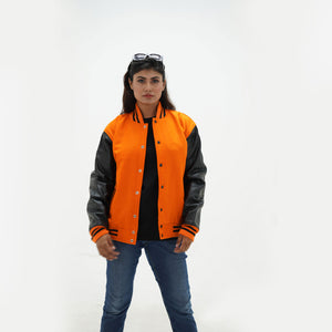 quarter view of women's orange and black letterman jacket highlighting snap buttons, side pockets, and bold color contrast