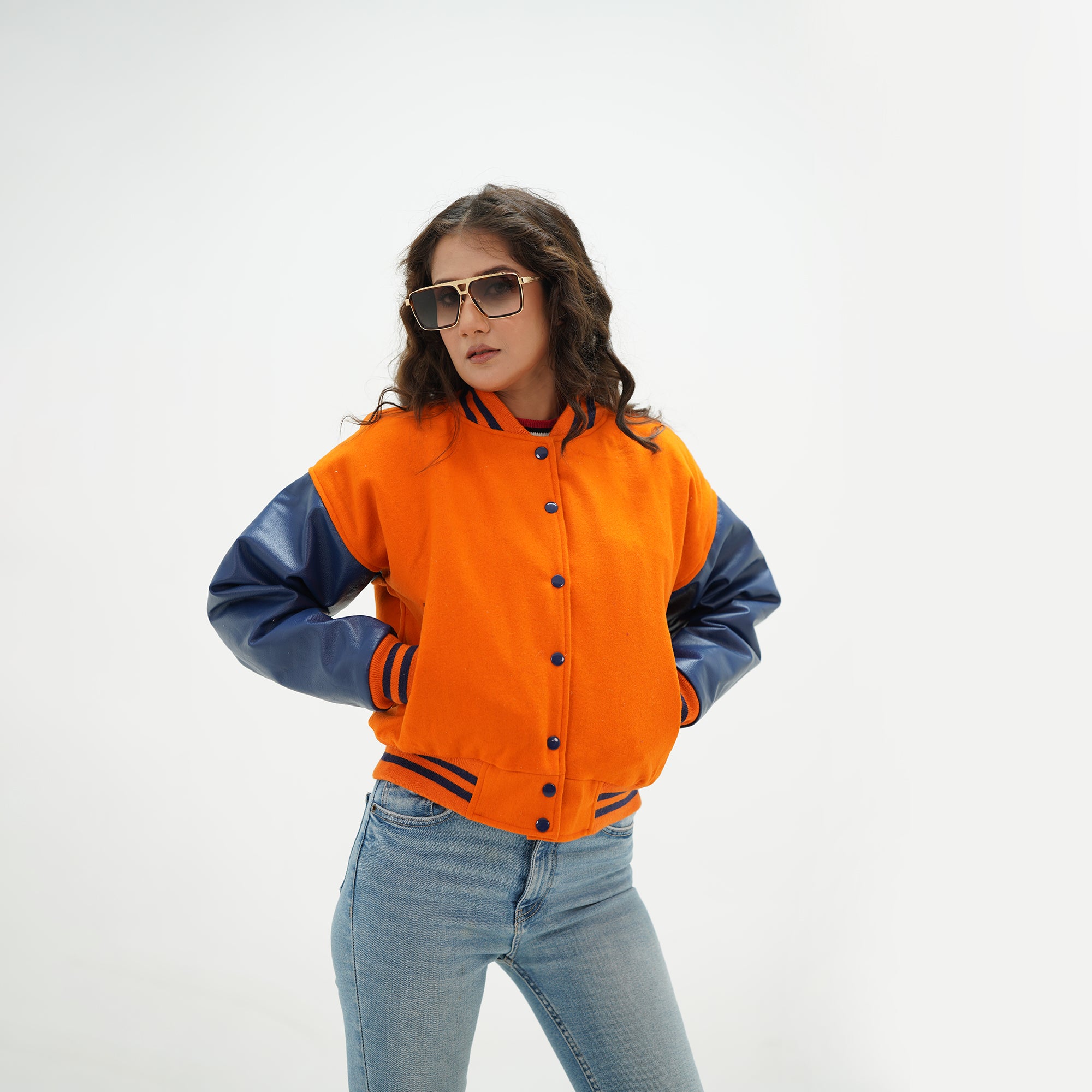 Side angle of women's orange and plum cropped varsity jacket showing java plum leather sleeve detail, ribbed cuffs, and cropped waist length