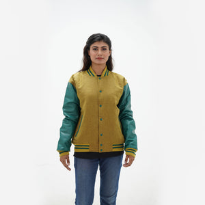 Three-quarter view of women's camel varsity jacket with green leather sleeves highlighting snap buttons, pocket placement, and wool texture