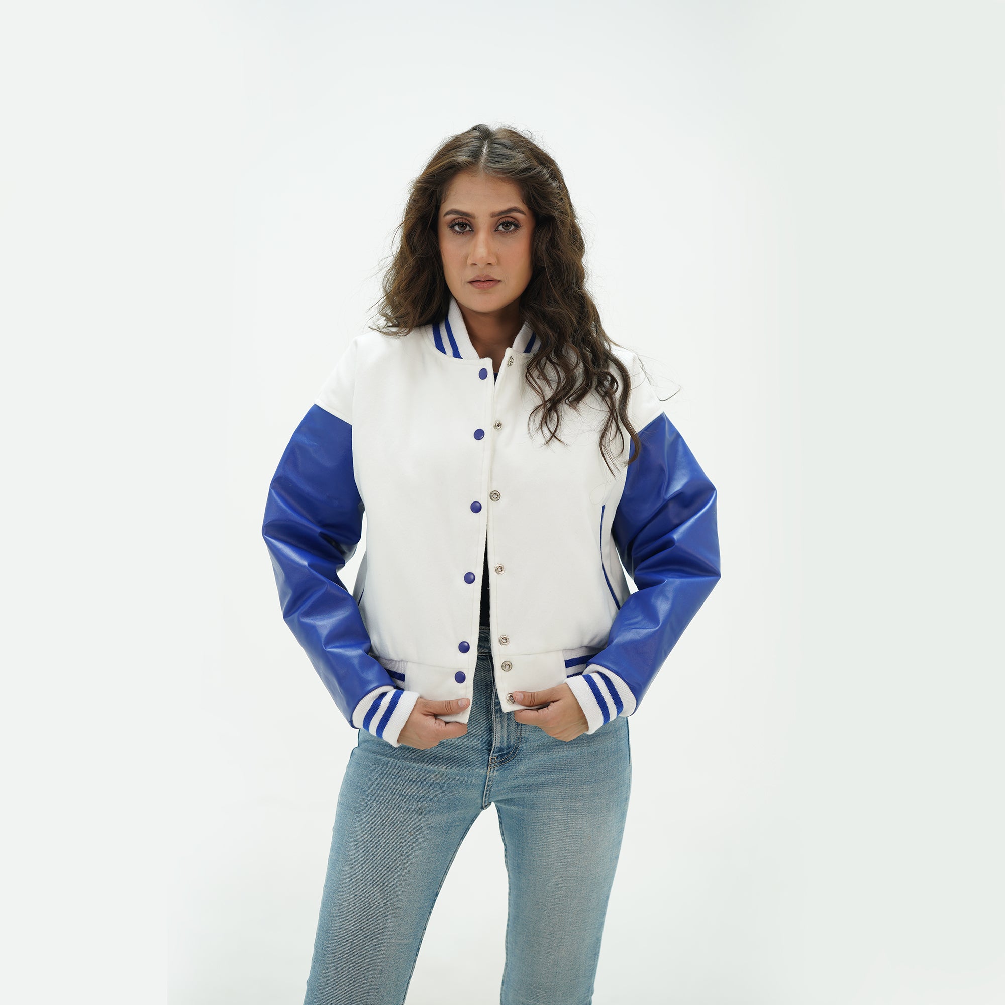 Three-quarter view of women's white and blue crop varsity jacket highlighting snap buttons, cropped waist, and fresh white-blue color scheme
