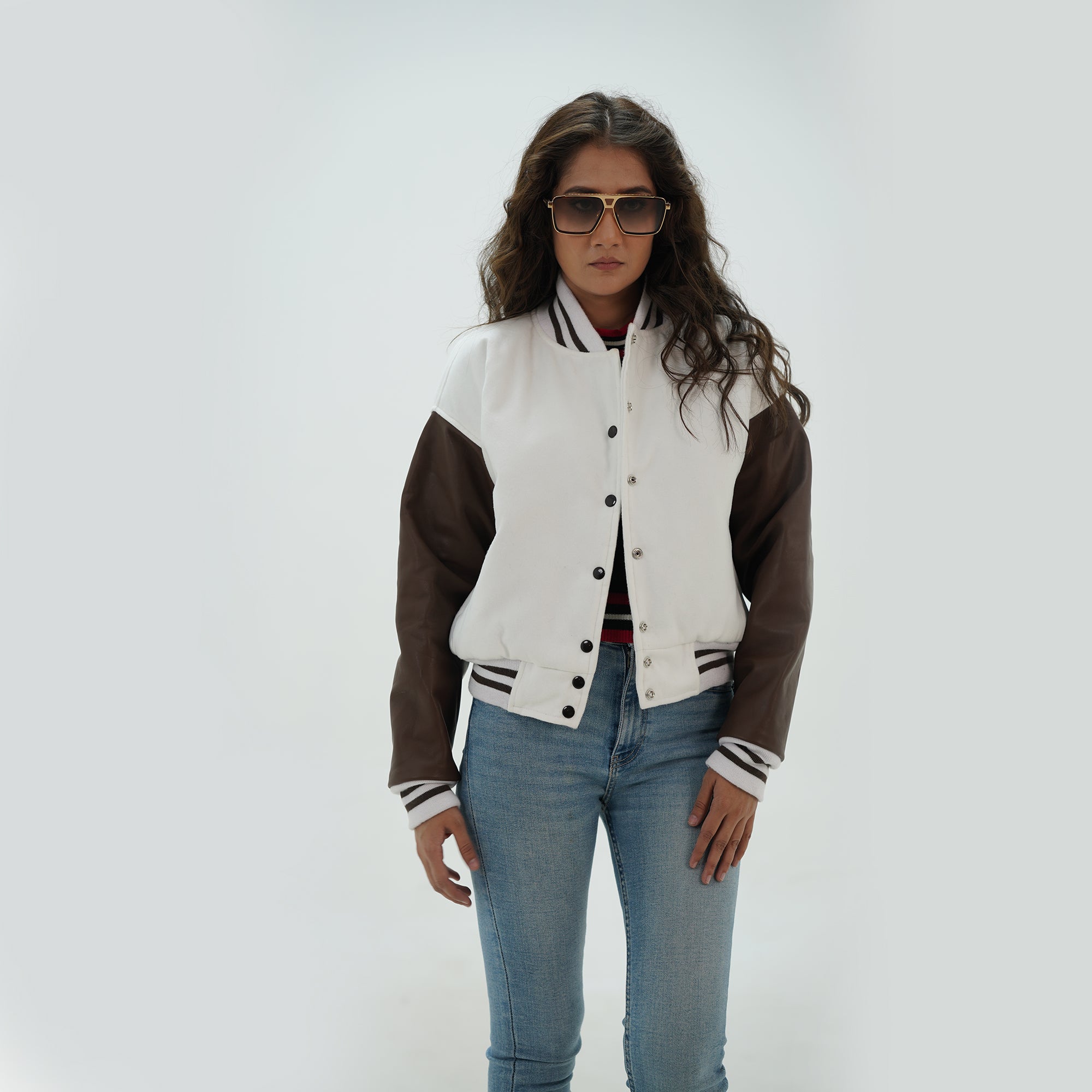 Three-quarter angle of women's white and chocolate brown varsity jacket highlighting snap buttons, side pockets, and elegant white-chocolate brown color pairing