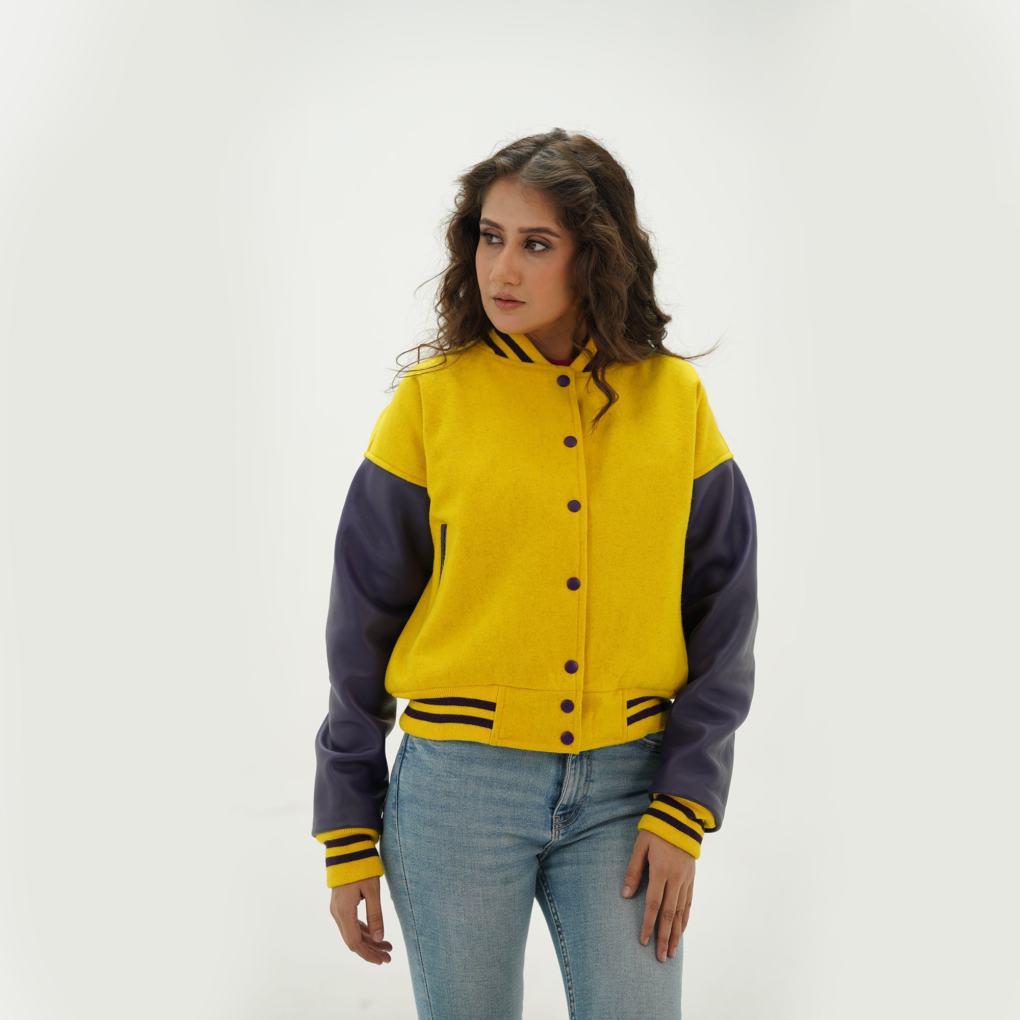 Side profile of women's yellow and blue letterman jacket showing blue leather sleeve detail, ribbed cuffs, and tailored feminine fit